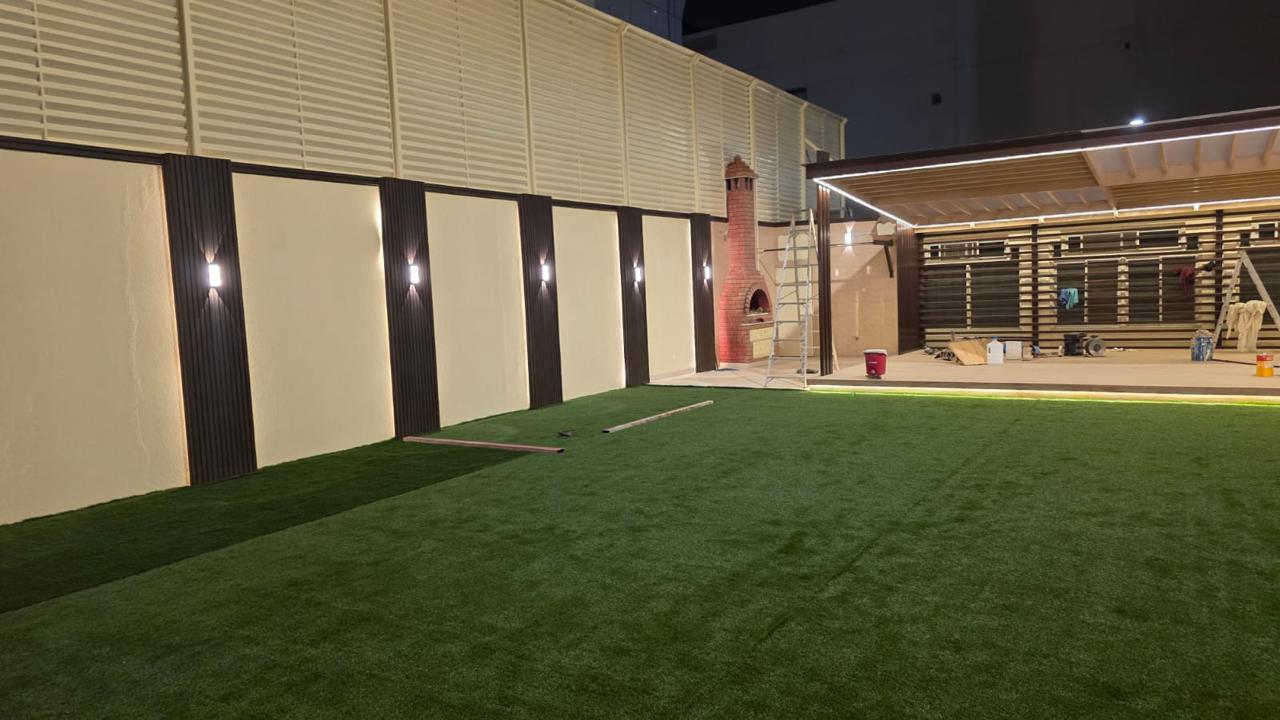 ديكور جدار خارجي مع عشب صناعي وإضاءة